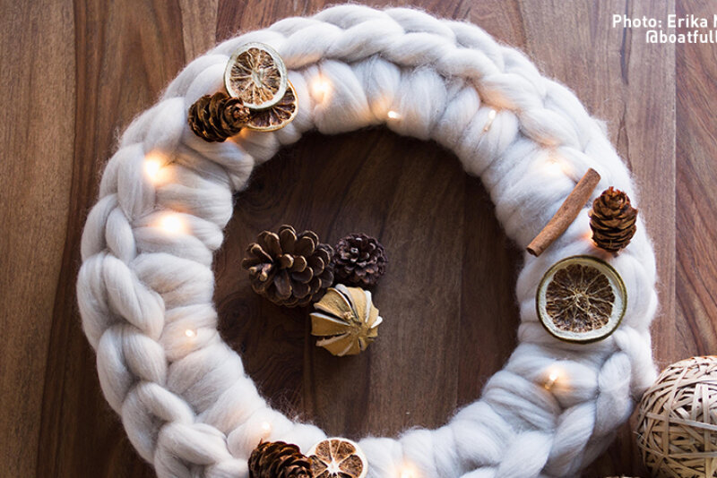 A circular wool wreath with pine cone and dried orange decoration