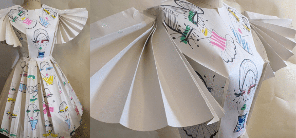 A dress on a mannequin made out of paper with drawings on.