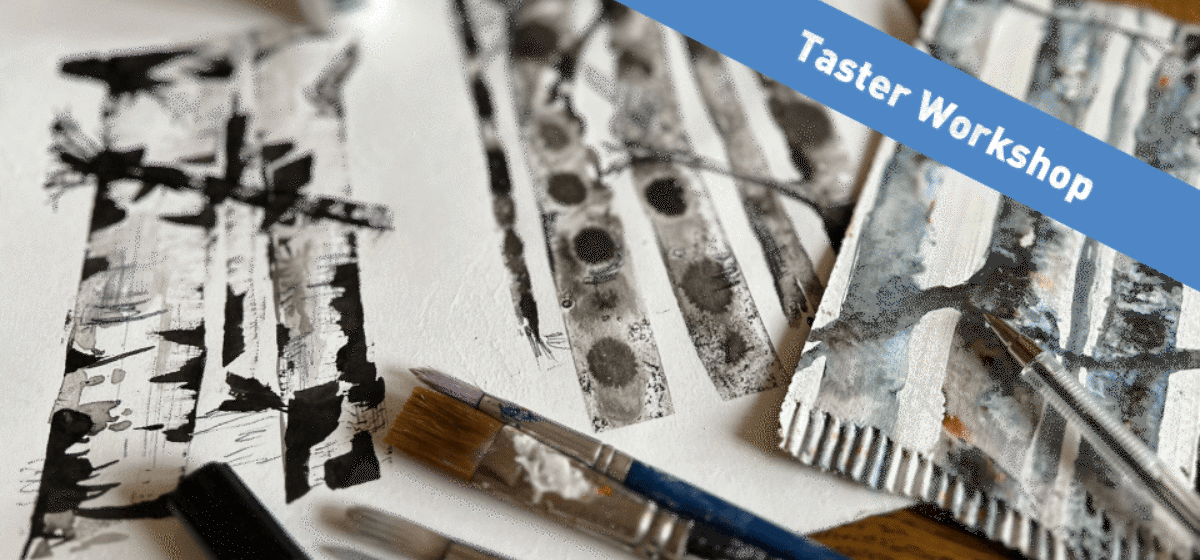 Two pieces of paper with black and white tree drawings next to a paint brushes