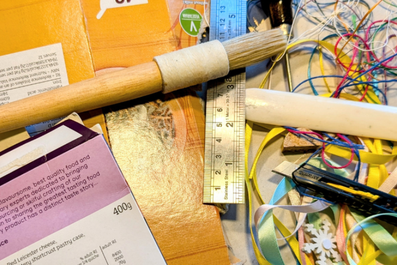 A collection of cardboard, ribbon, a ruler and a brush