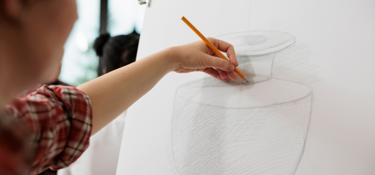 Young person's hands holding pencil to draw on a white canvas