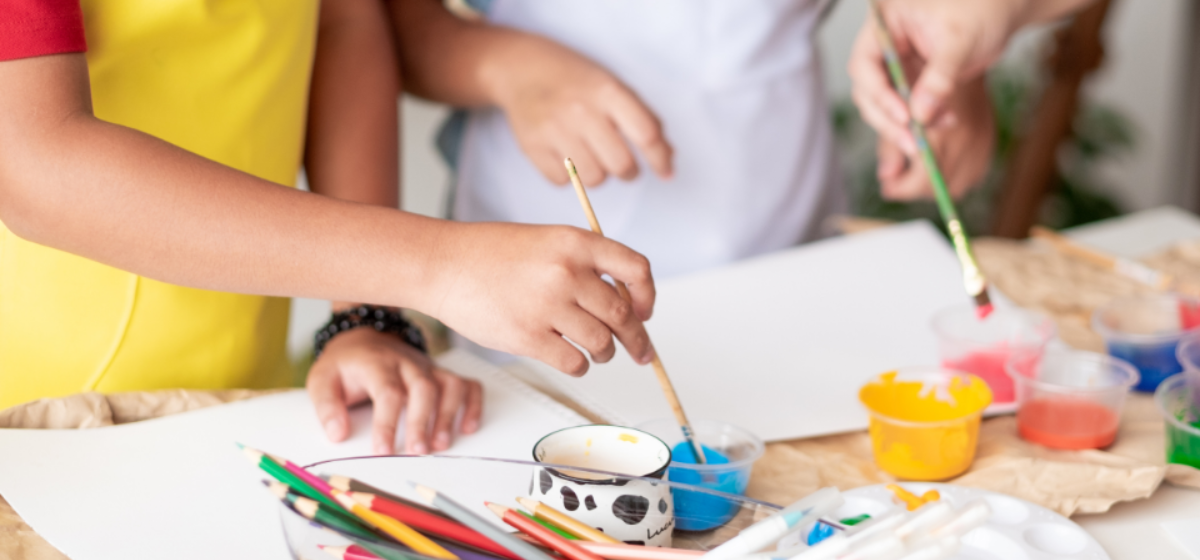 a children's workshop table full of painting materials and paper