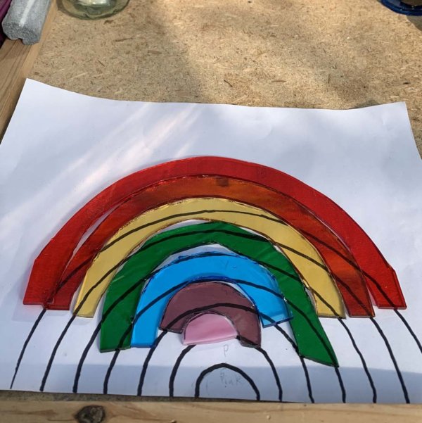 A4 white paper with a rainbow stencil drawn on it with sections of glass of different colours in a arc rainbow shape on top.